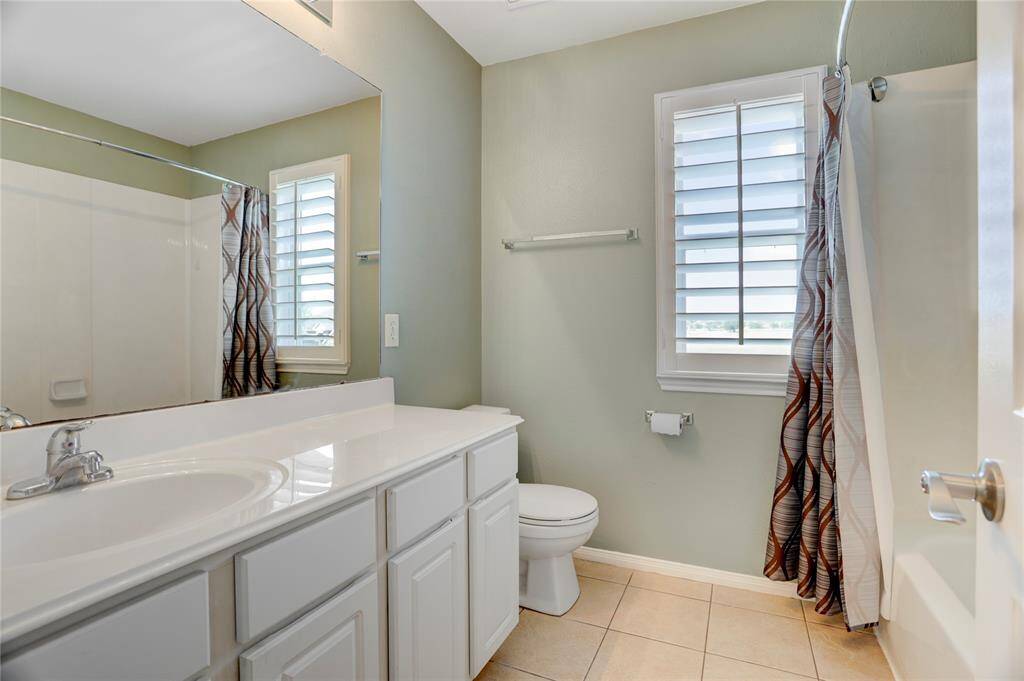 This is the second upstirs bathroom features with a white vanity, and a large mirror. It has a window with shutters for natural light.