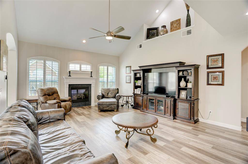 Spacious living room with high ceilings, featuring a cozy fireplace and large windows for natural light. Ideal for relaxation and entertainment.