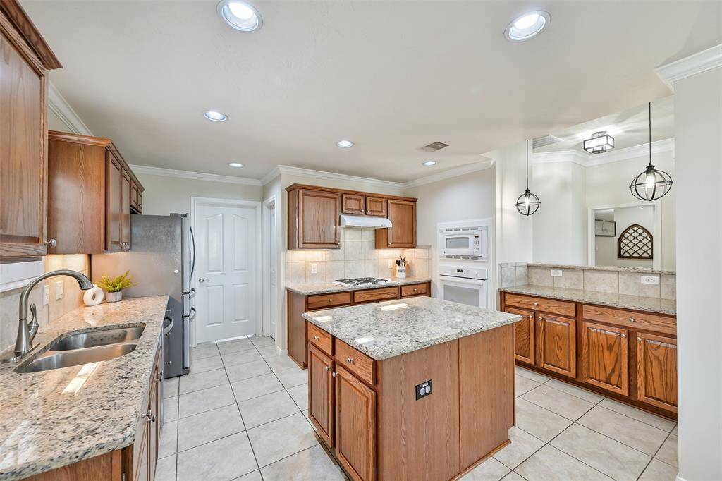 Abundant cabinetry, granite counters, a large center island, and a built-in planning desk add function and flexibility to this well-appointed kitchen, complete with stainless appliances and under-cabinet lighting.
