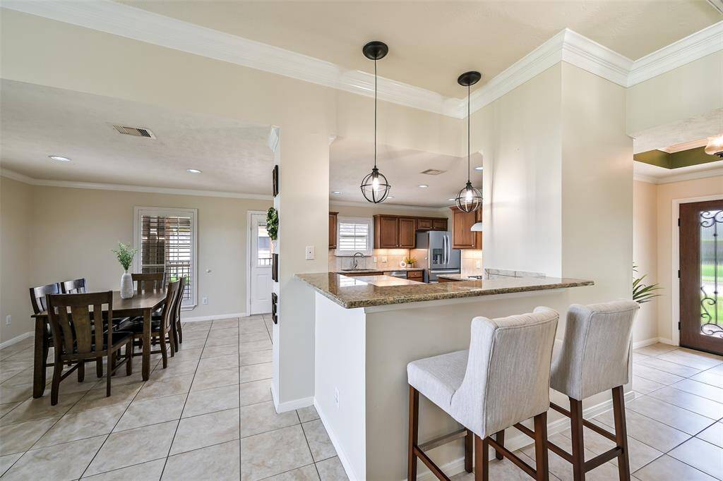 Charming breakfast bar with granite counters and pendant lighting overlooks the open-concept kitchen and dining area, creating an inviting space for casual dining and entertaining.