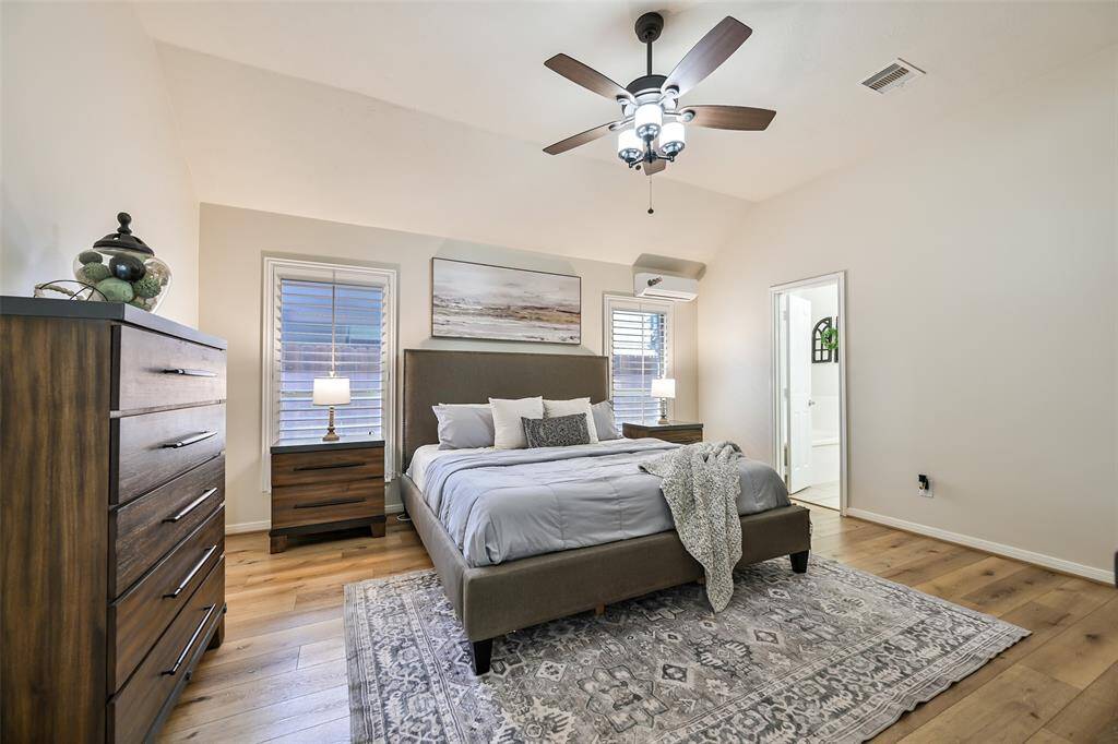 Spacious primary suite features wood-look flooring, plantation shutters, high ceilings with a modern ceiling fan, and a ductless mini-split for personalized climate control.