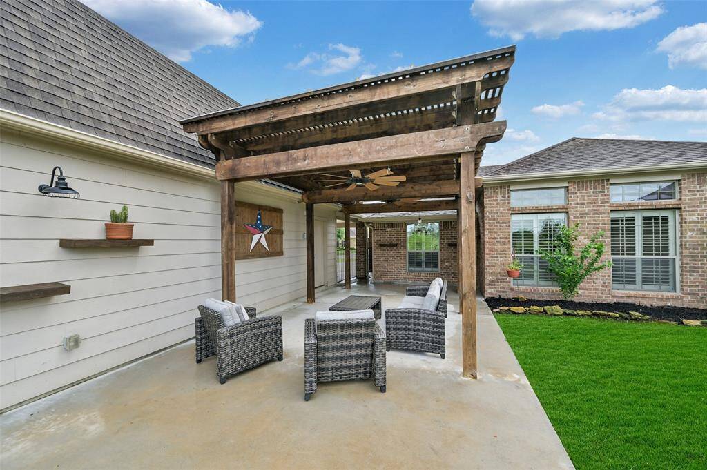 Covered patio with a charming wood pergola offers a shaded retreat perfect for outdoor entertaining, complete with ceiling fan and relaxing views of the lake.