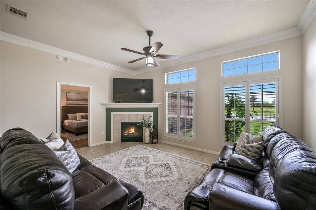 The spacious family room boasts fresh neutral paint, crown molding, and abundant natural light through a trio of tall windows with timeless plantation shutters. A cozy gas fireplace anchors the space, while tile floors offer durability and easy maintenance.