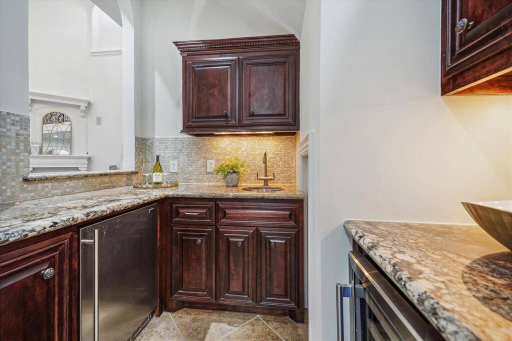 Perfect for entertaining, the sophisticated wet bar features granite surfaces, a wine fridge, and elegant tilework—effortless refinement at your fingertips.