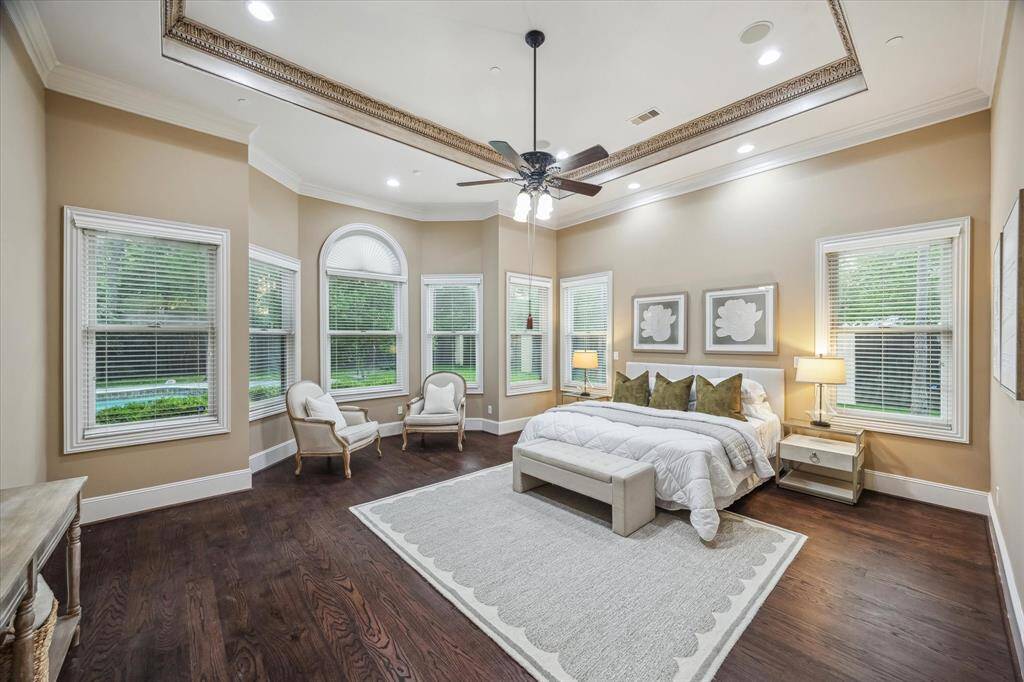A grand retreat with elegant crown molding, wide-plank hardwood floors, and a wall of windows overlooking the pool—luxury, light, and tranquility in perfect balance.