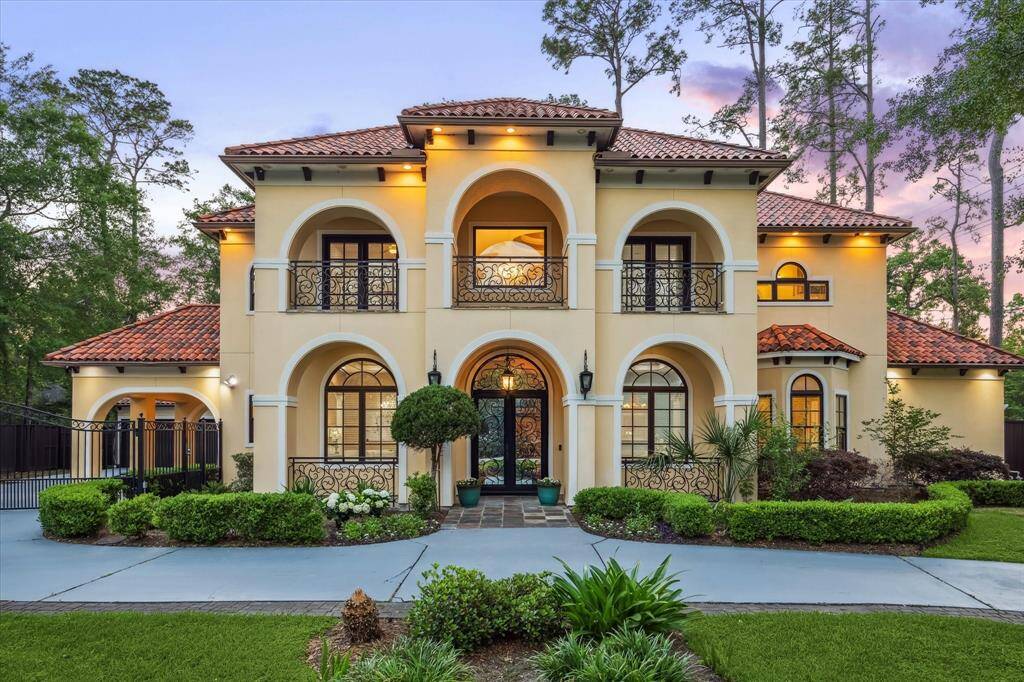 Positioned on a premier corner lot, this stately residence showcases pristine stucco, wrought iron details, and glowing evening ambiance.