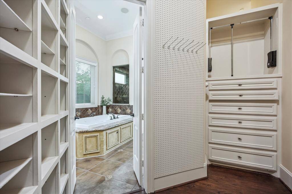 Custom closet built-ins and shoe shelving make organization effortless while offering easy access to the luxe soaking tub and dressing space beyond.