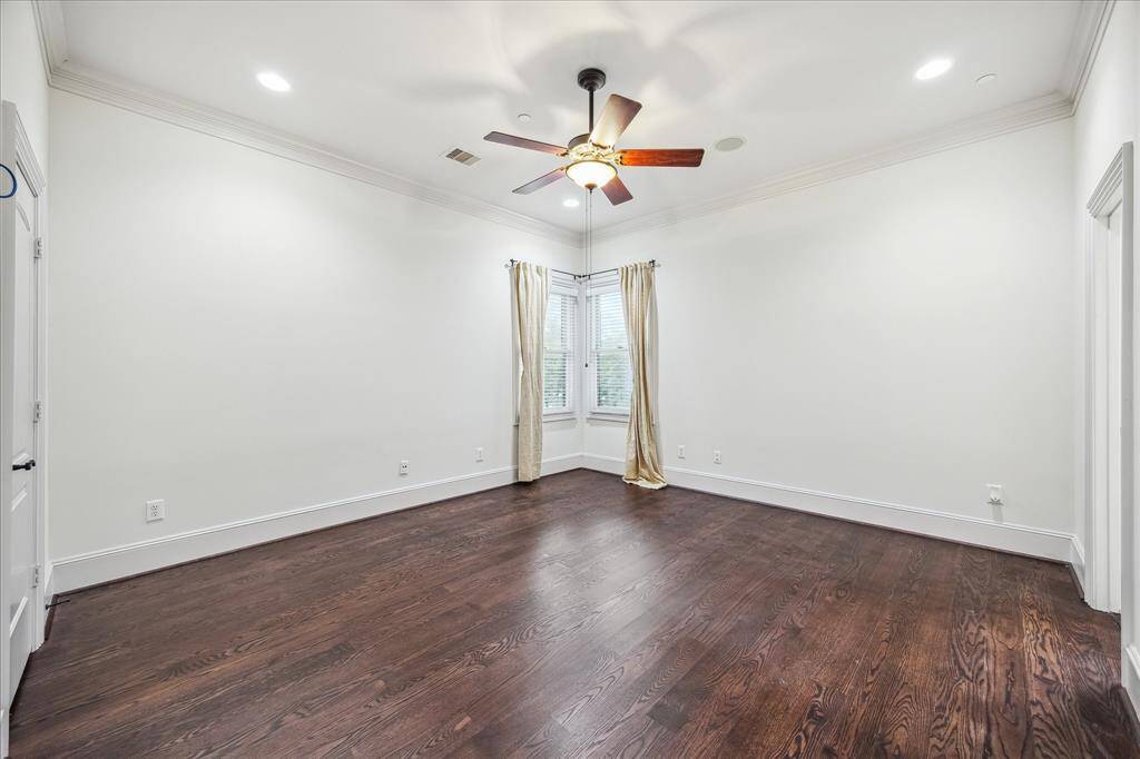 Spacious and serene, this upstairs bedroom features hardwood floors, crown molding, and an en-suite bath for added privacy and comfort.