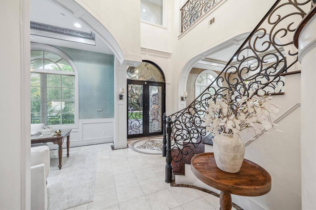 Step into timeless elegance—this grand entry features soaring ceilings, custom ironwork, and a dramatic curved staircase that sets the tone for the entire home.