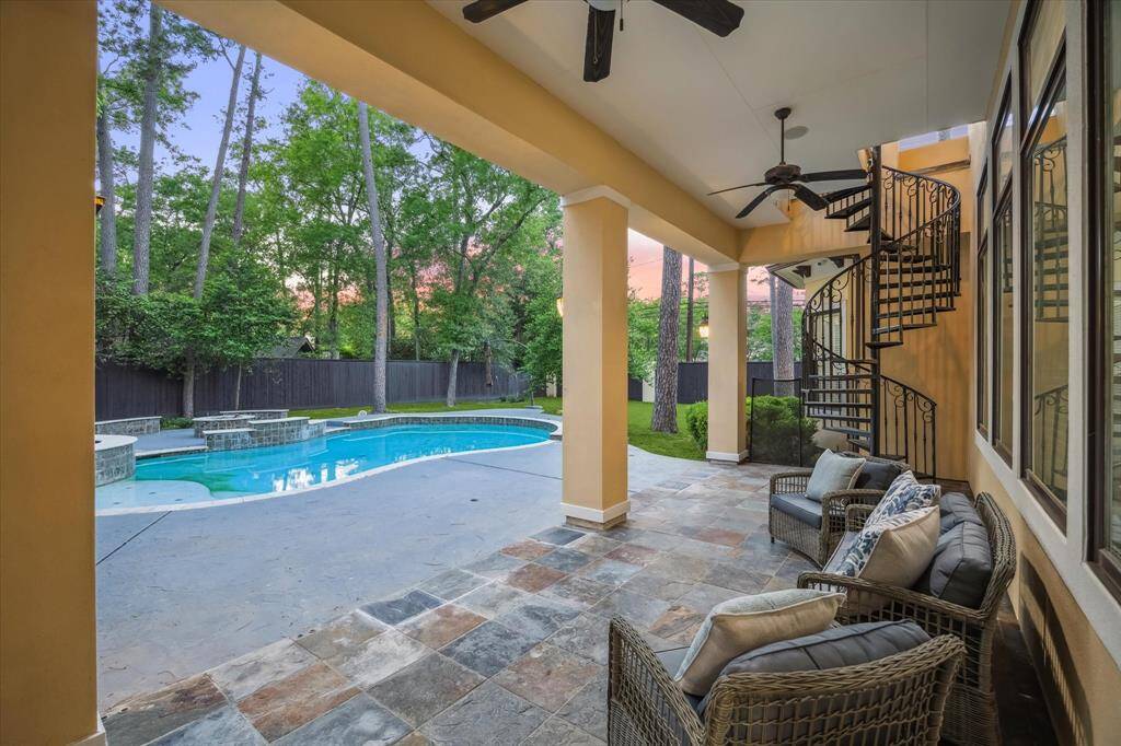 Enjoy serene evenings under the covered patio, complete with dual ceiling fans and a stunning wrought iron spiral staircase to the upper balcony.