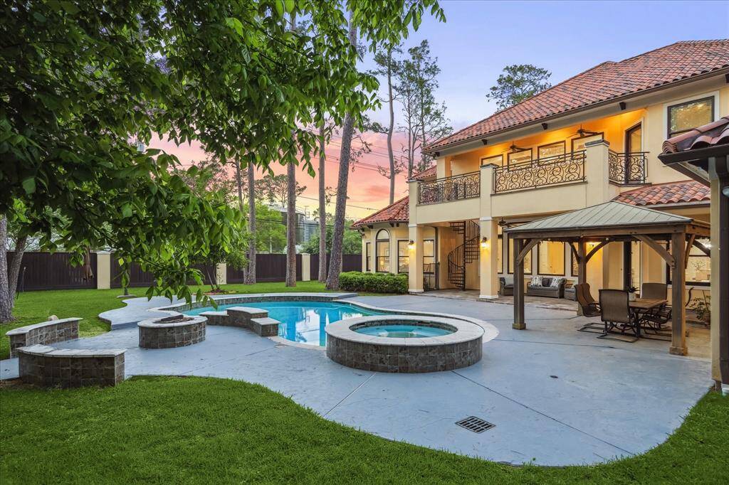 Resort-style pool and elevated spa set the stage for relaxation and entertaining, surrounded by lush green lawn and custom stone decking.