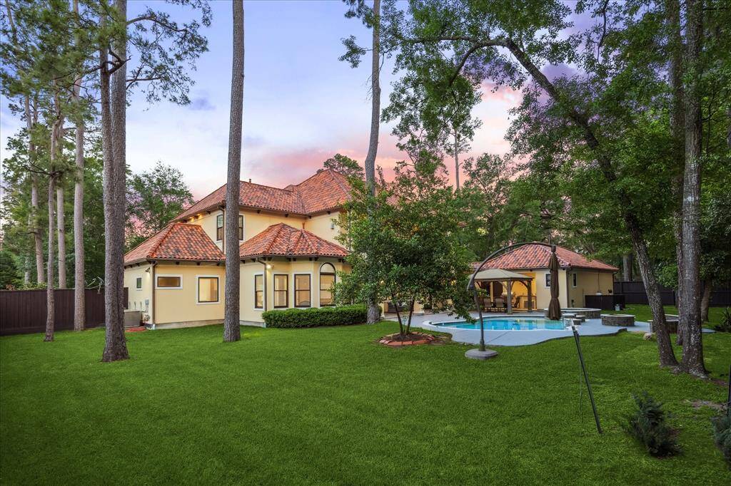 Expansive backyard framed by mature trees offers a peaceful, private setting with room to roam or relax.