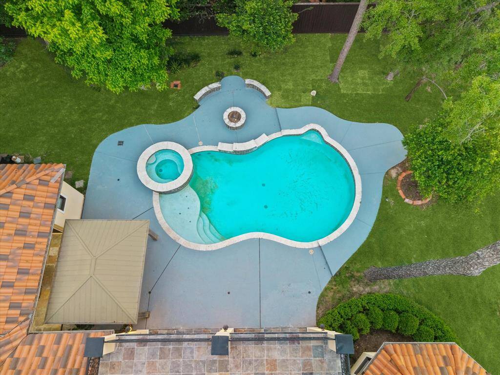 Soak in the resort-style layout from above, showcasing the sparkling pool, spa, firepit, and ample patio space ready for summer gatherings.