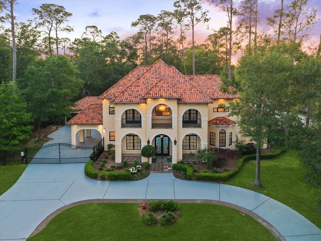 Golden hour highlights every detail of the elegant tile roof, symmetrical balconies, and stately architecture framed by mature trees and manicured landscaping