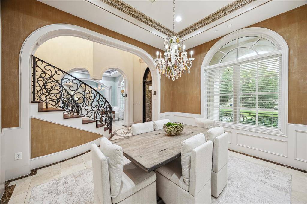 Formal dining area features gleaming accent walls, an ornate crystal chandelier, and elegant columns—perfect for hosting with flair.