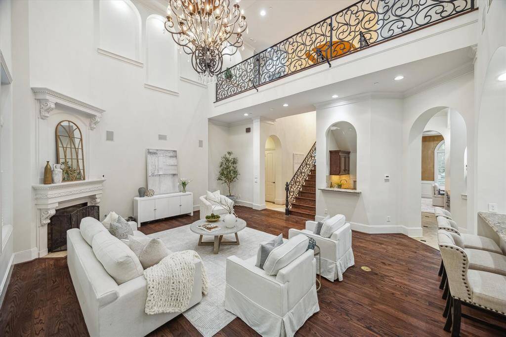 Soaring ceilings and architectural arches elevate this spacious living room, with a sweeping staircase and open flow into the kitchen and foyer.