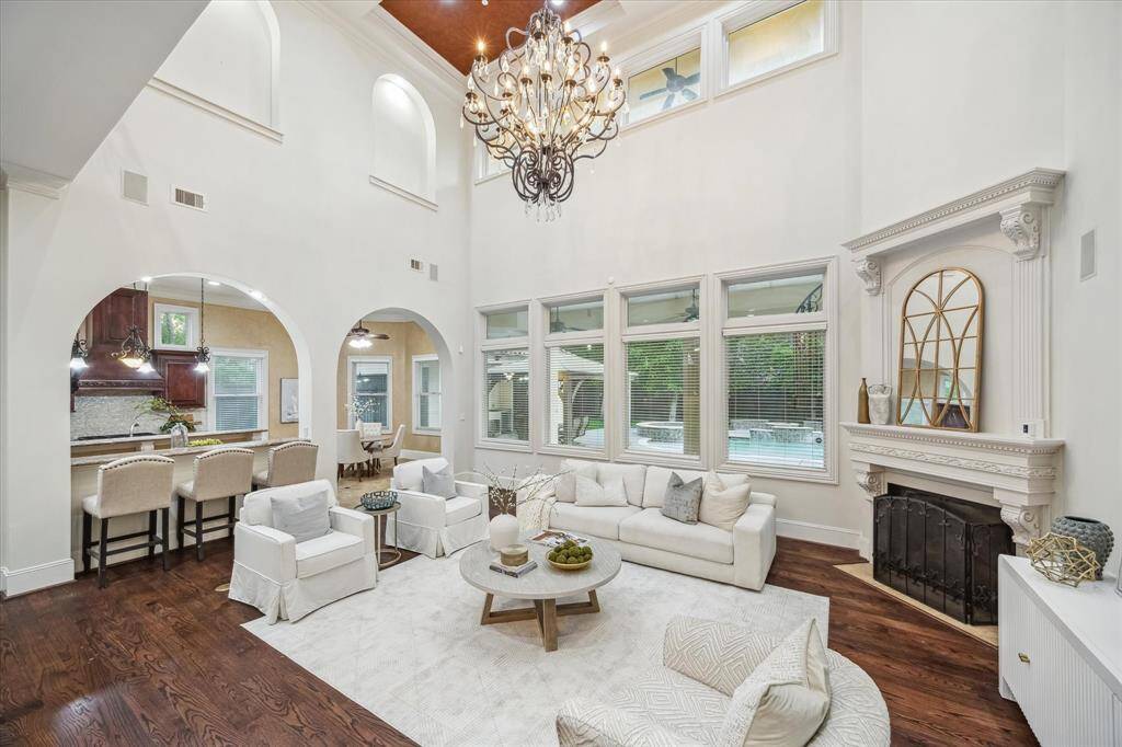 Wall-to-wall windows flood the room with natural light and provide serene views of the backyard oasis. The ornate fireplace anchors the space with elegance.