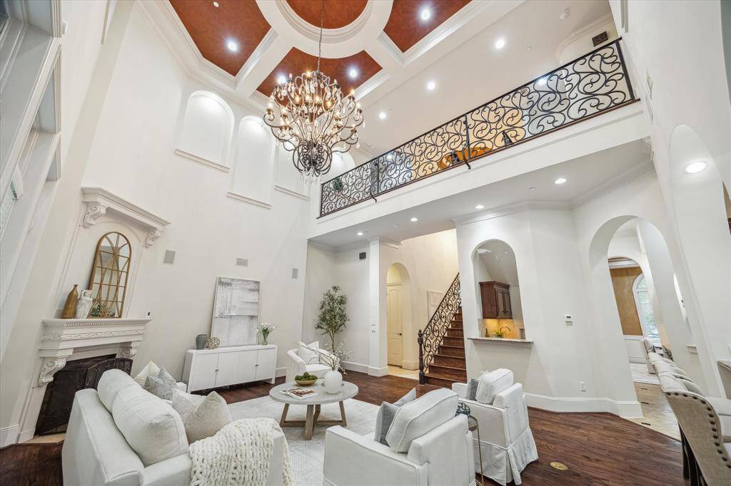 An opulent chandelier and wrought iron balcony railing add dramatic flair to the living area’s grand scale and ceiling height.