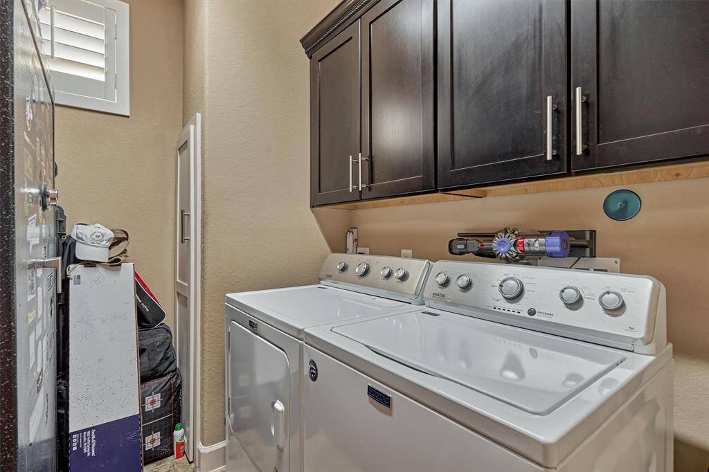 The first floor laundry room has storage cabinets and laundry chute from the third level.