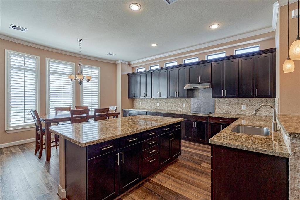 The spacious kitchen offers granite countertops, rich stained wood cabinets and ample storage. A breakfast area is bright with natural light and overlooks the front yard.