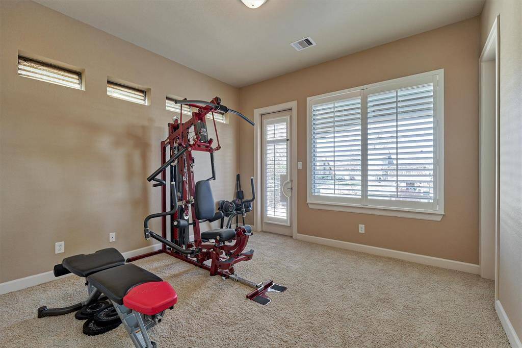 The first floor bedroom is currently being used as a home gym. It features a glass door that opens to the back porch while a large window offers a scenic view of the lake.