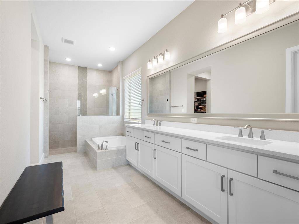 The en suite primary bathroom boasts a modern design with dual sinks, a large mirror, and sleek cabinetry.