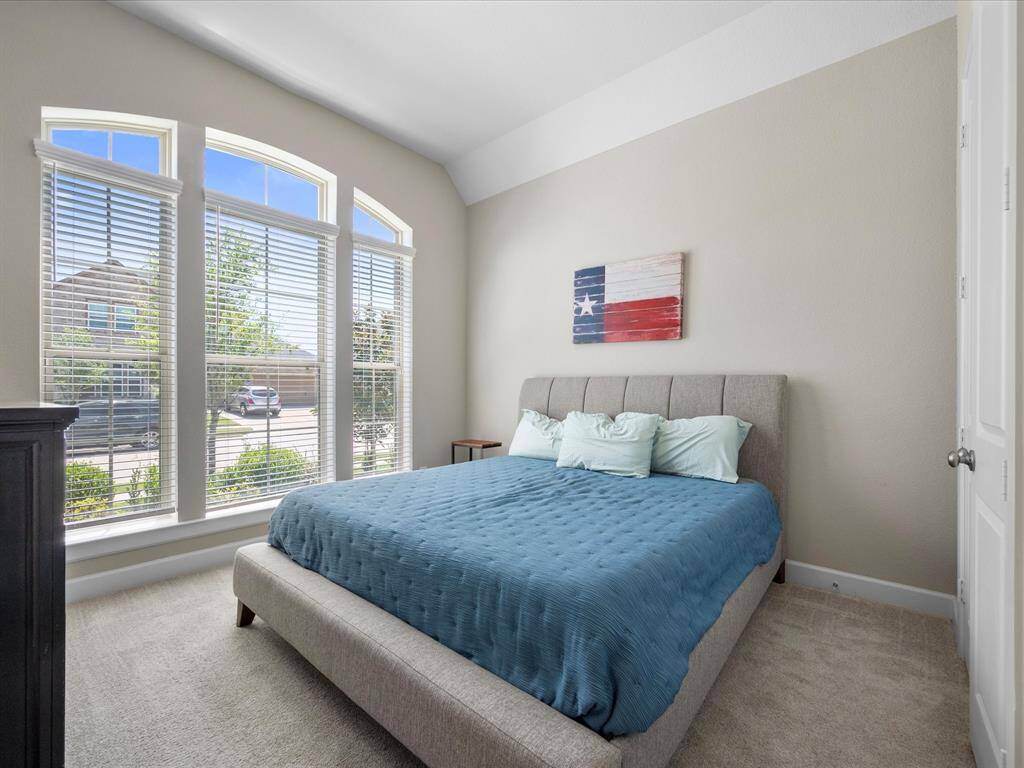This secondary bedroom showcases large arched windows that fill the space with natural light, complemented by neutral walls and a private en suite bath for added comfort and convenience.