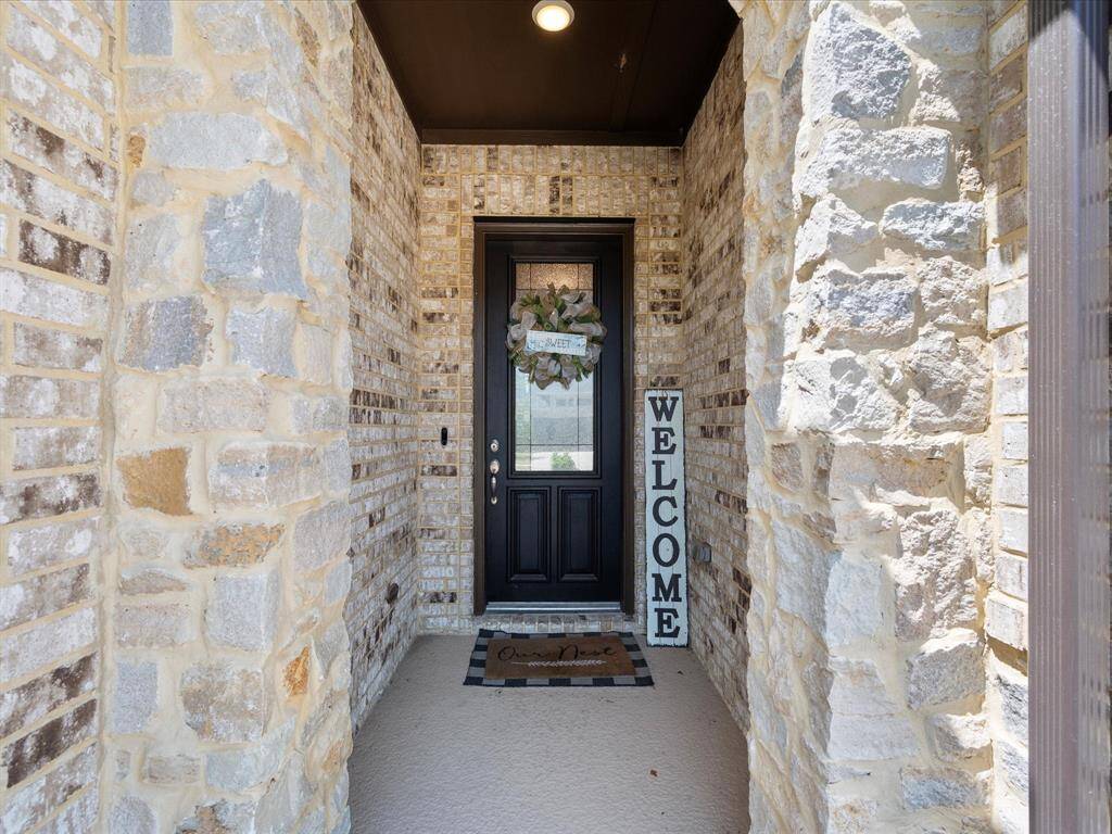 Elegant entryway featuring refined stone and brick accents, complemented by a rich wood front door with stunning leaded glass detailing—setting the tone for stylish living.