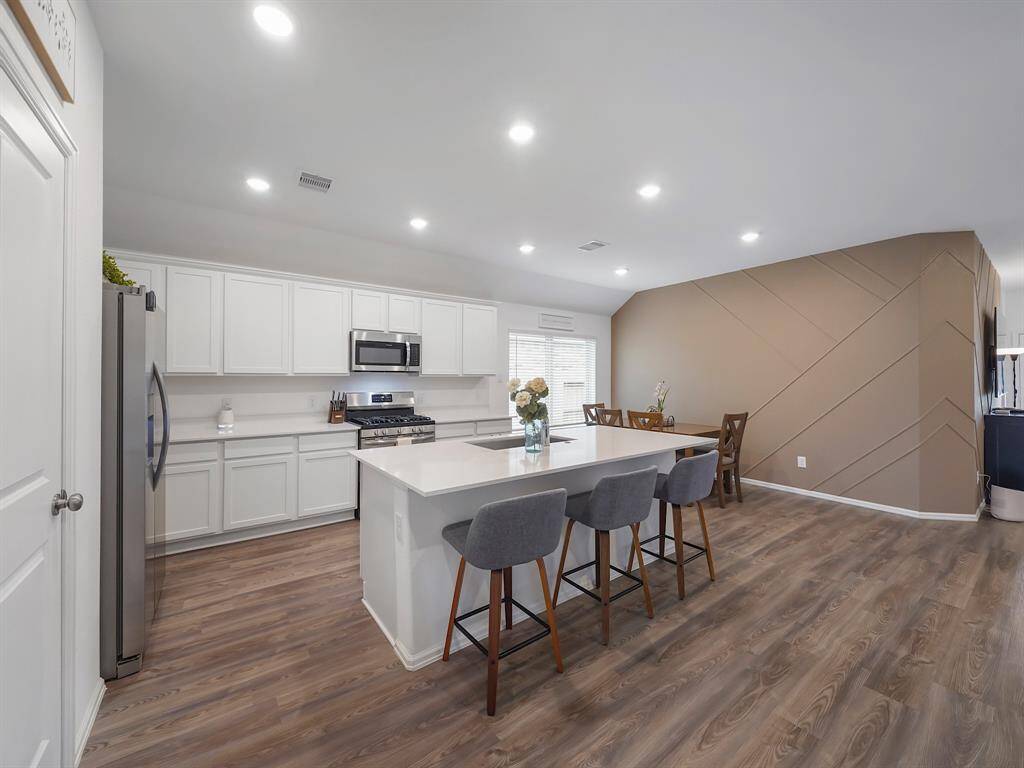 The heart of the home is the expansive island kitchen, boasting 36'' designer cabinets, sparkling quartz countertops, and sleek stainless steel appliances, perfect for culinary enthusiasts and family gatherings.