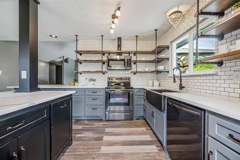 The subway tile backsplash, open shelving, and updated light fixtures are truly designer touches of this renovated kitchen.