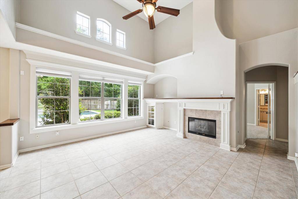 The spacious living room is positioned at the rear of the home, featuring a wall of windows that frame serene views of the pool, spa, and beautifully landscaped backyard. The fireplace mantel is a focal point of this room along side the arched niche perfect for an entertainment center.
