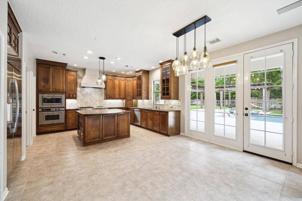 Located adjacent to the kitchen and breakfast area, French doors lead into the formal dining room. Floor to ceiling windows provide abundant natural light and offer stunning views of the custom pool.