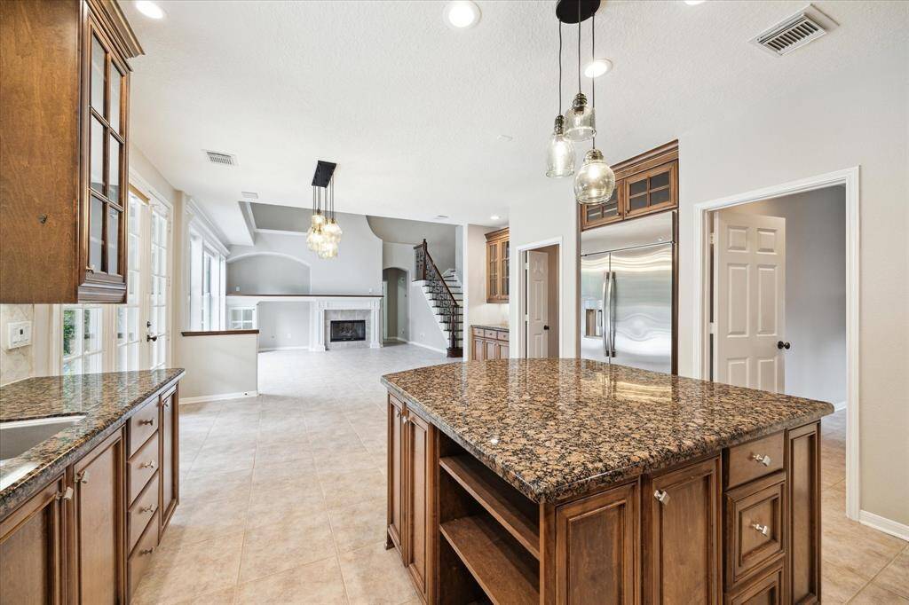 The light-colored tile beautifully contrasts with the rich chestnut cabinetry and granite countertops.