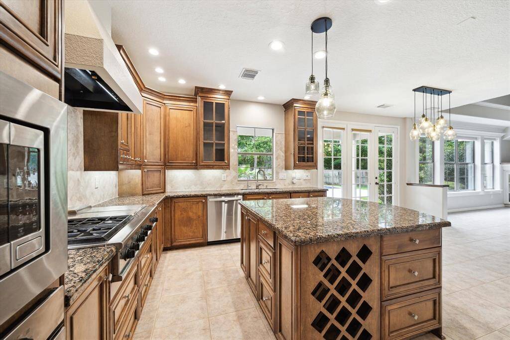 An ideal chef's kitchen, spacious enough for hosting, entertaining, and prepping meals for any occasion. It features abundant cabinetry, storage, granite countertops, and a large kitchen island.
