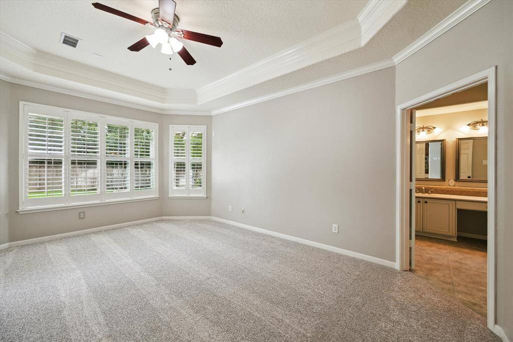 Another view of the expansive primary bedroom, showcasing its generously sized layout and double doors that lead into the primary bathroom.