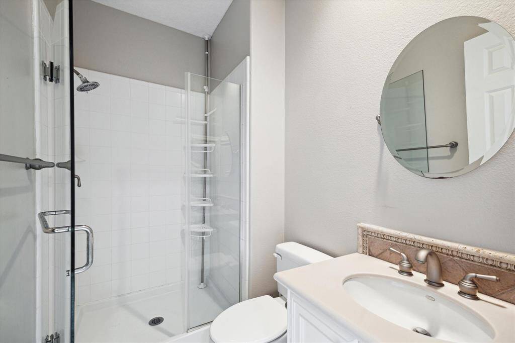 The en-suite bathroom of the guest room features a seamless walk-in shower and a circular mirror, providing a polished and elegant finish to the space.