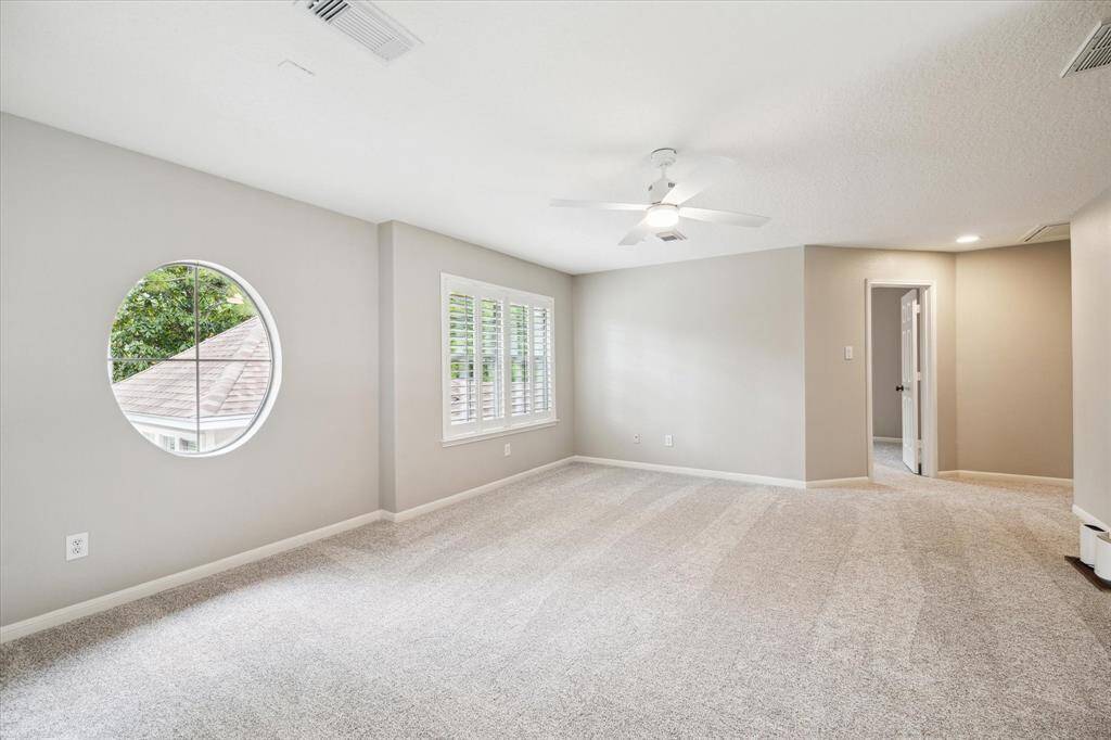 Situated on the second floor, this expansive game room boasts a high ceiling with a ceiling fan and is filled with natural light that filters through the plantation shutters.