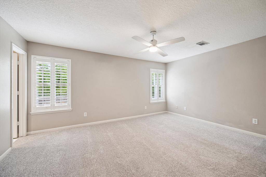 Spacious secondary bedroom on the second level featuring plantation shutters, a large walk-in closet, and an attached full bathroom with dual sinks.
