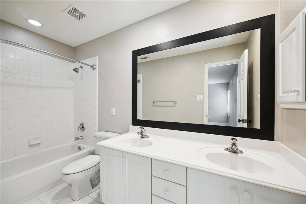 The secondary bathroom featuring the dual sinks and framed mirror.