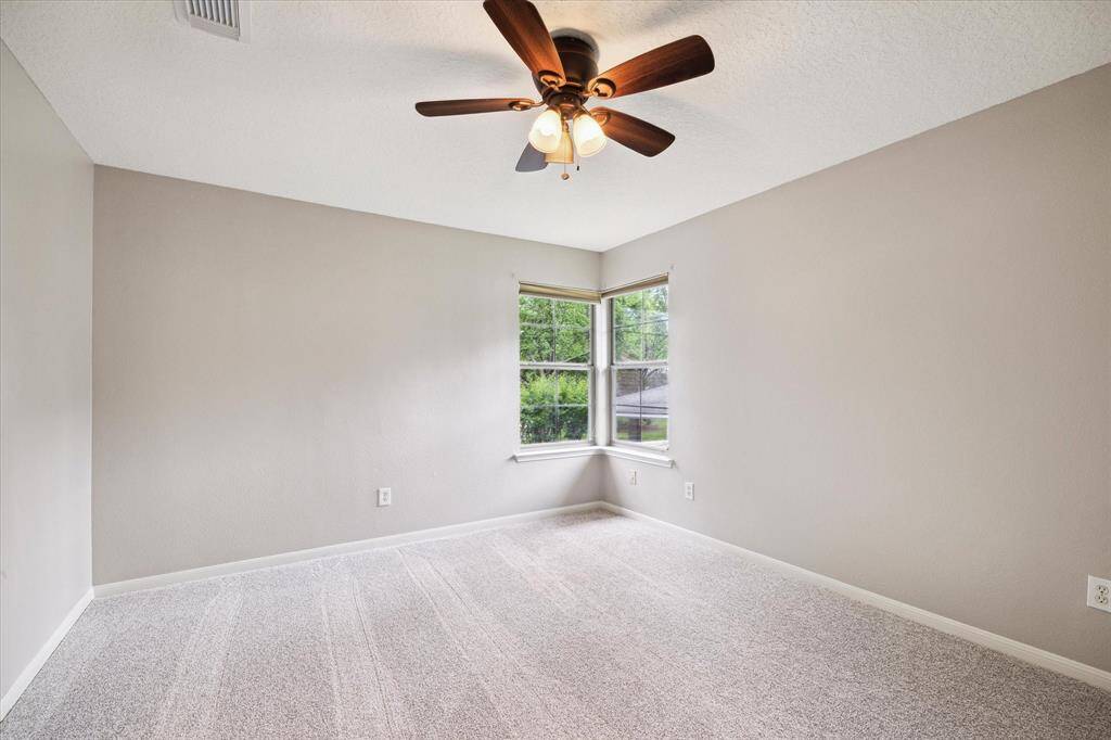 A secondary bedroom with high ceilings, windows viewing the front of the home, and an attached full bathroom conveniently connected to the closet space.