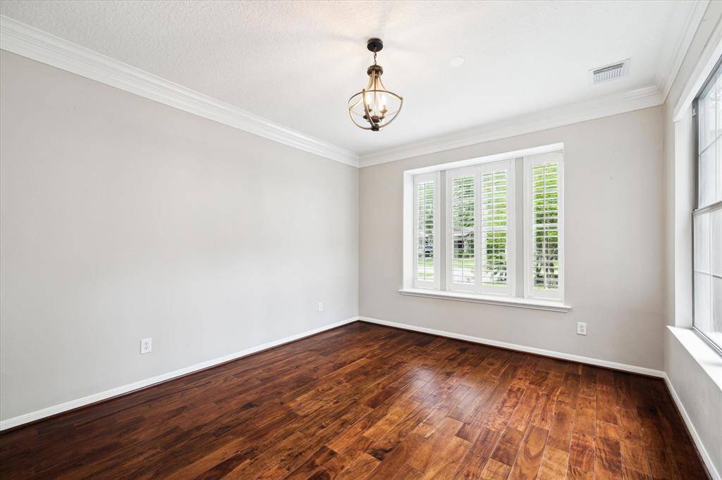 A front-facing flex room which could function as a study or formal living room showcases rich engineered wood flooring, an abundance of natural light, and a charming view of the gated courtyard.