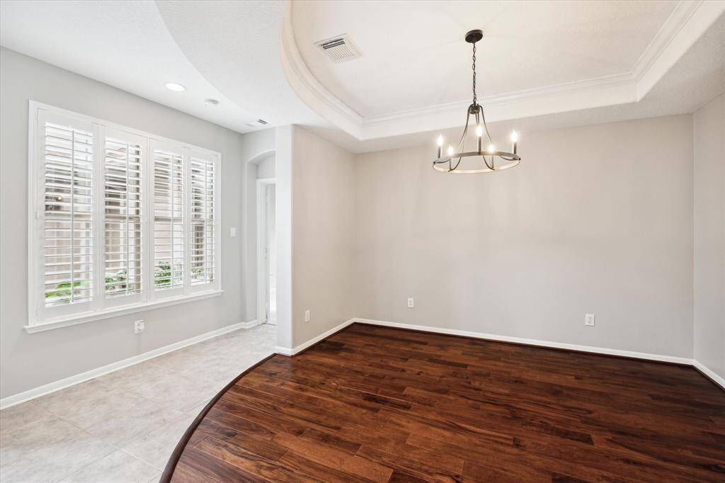 Upon entering, the home impresses you with its light-filled interiors, featuring a polished engineered wood and tile flooring completed by a sophisticated designer color palette. To the left, an expansive formal dining room offers elegant space for entertaining, while to the right, a private study or versatile flex room offers a quiet retreat or flexible living option.