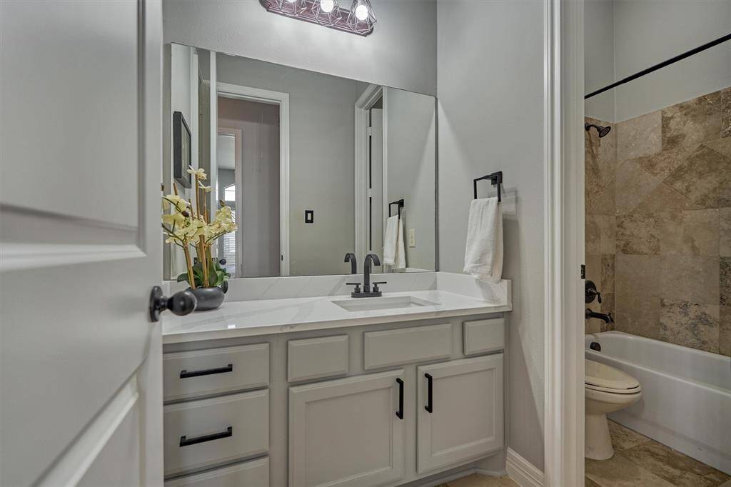 Secondary bath room has quartz counters and updated lighting and hardware.