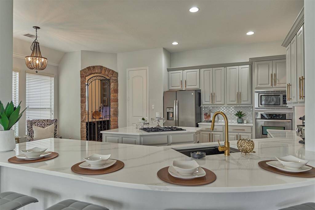 Beautiful quartz counters and breakfast bar sits four comfortably. Notice the gold faucet and updated hardware.