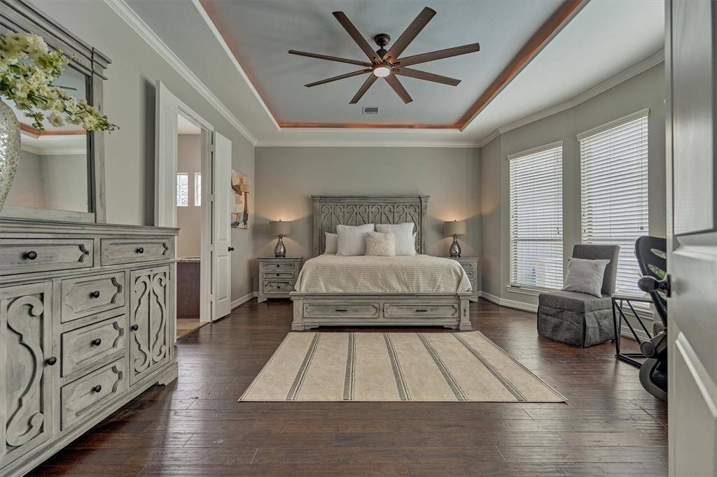 The primary bedroom features warm hardwood floors and ample space. Whether you’re unwinding with a book or catching up on late-night work, there’s plenty of room for a desk and a cozy seating area.