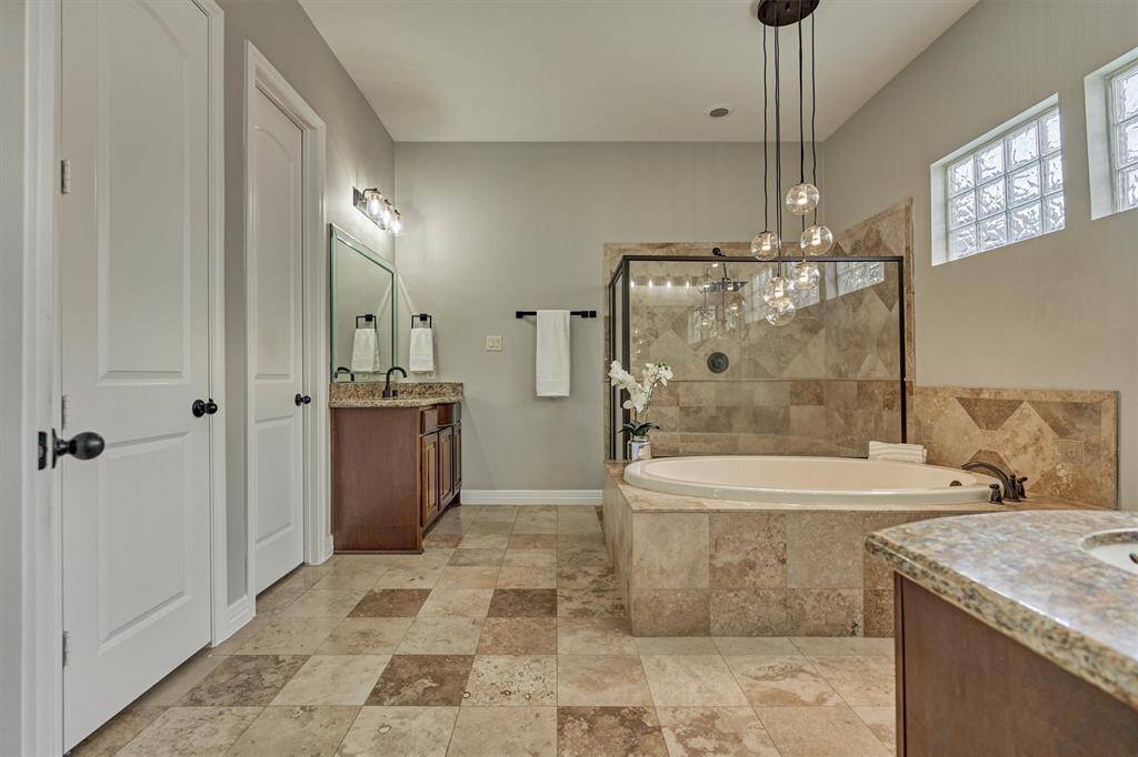 The primary bathroom boasts stunning tile flooring, dual sinks, a separate shower and tub, and stylish overhead lighting for a touch of fun.