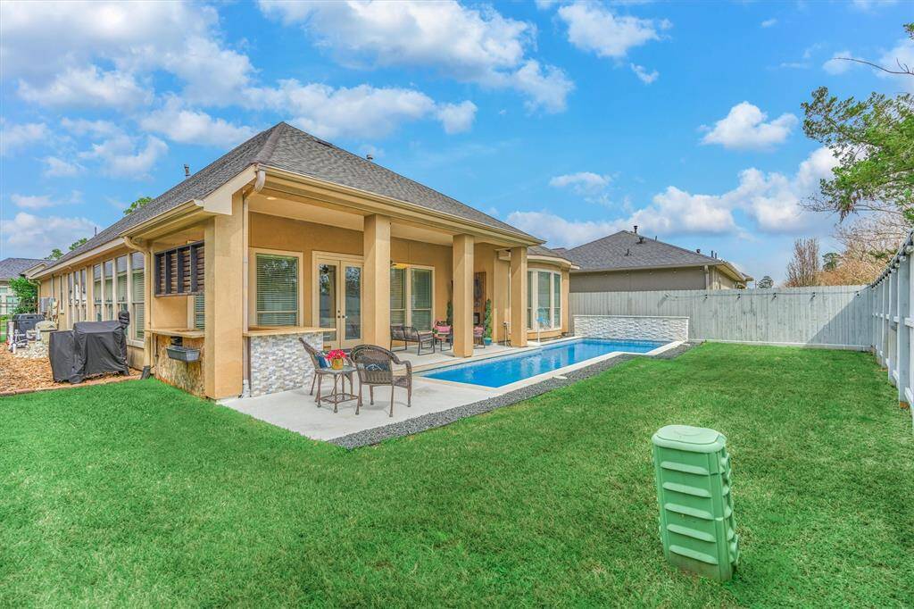 This spacious yard is perfect for pets or play! The cocktail pool is a seamless fit for the outdoor space, complemented by a cozy fireplace with a seating area. Enjoy the outdoor kitchen with a bar, additional seating, and TVs—perfect for watching the game.