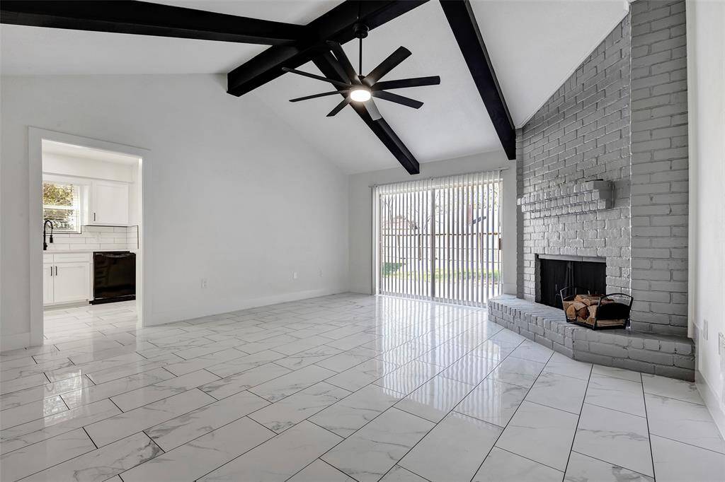 The inviting family room features a dramatic, floor-to-ceiling window that fills the space with natural light, complemented by a cozy corner fireplace, perfect for relaxing or entertaining.