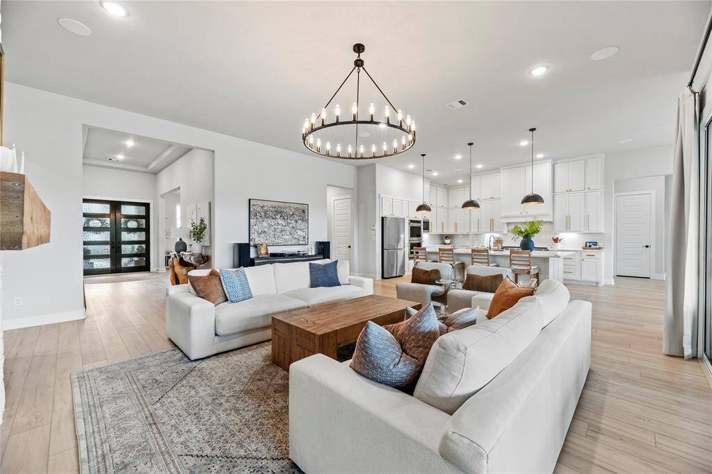 The family room features vinyl wood plank floors, modern light fixture, double door backyard access, recessed lighting, tall ceilings, and a gas/wood log fireplace.