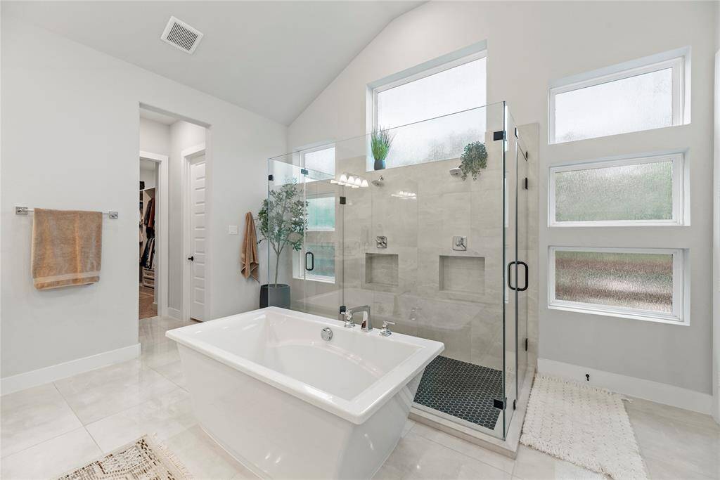 Relax in your deep soaking tub. The expansive walk-in shower, adorned with dual shower sprays, stunning tile work and a sleek glass front, offers a luxurious escape for a quick rinse or a refreshing retreat.
